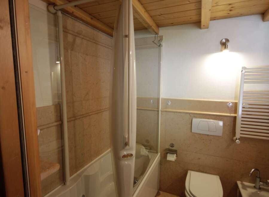 This bathroom boasts a bathtub with a sleek, folding shower screen, making it perfect for relaxation and functionality.