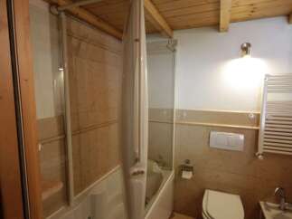 This bathroom boasts a bathtub with a sleek, folding shower screen, making it perfect for relaxation and functionality.