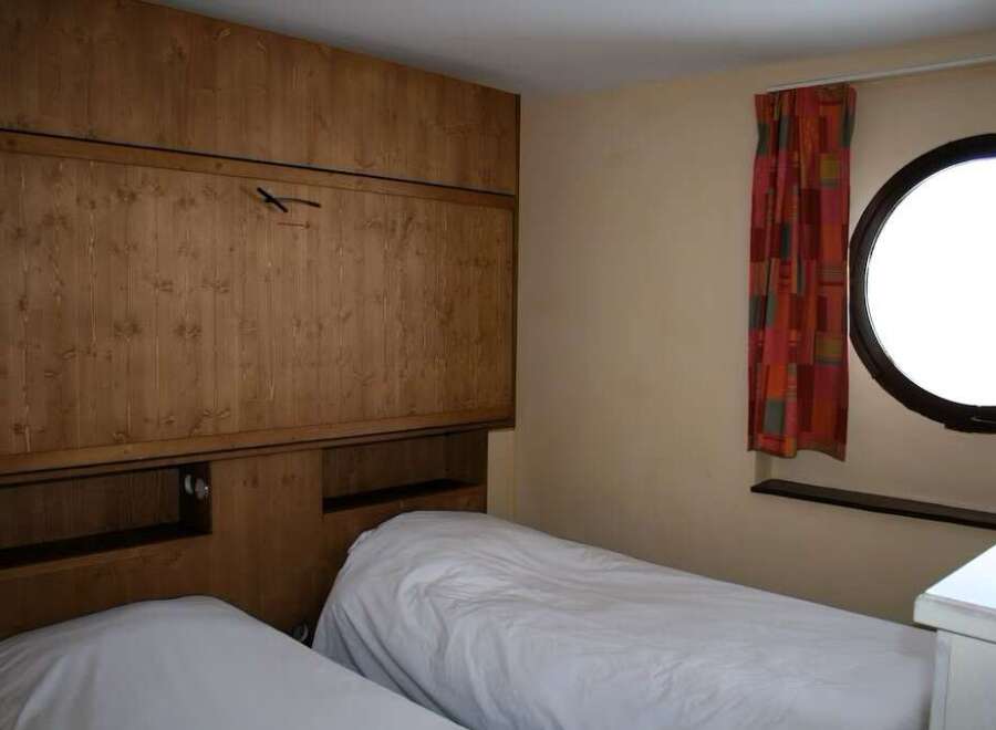 This cozy bedroom features a unique wooden wall design and two comfortable beds, perfect for a relaxing stay.