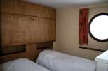 This cozy bedroom features a unique wooden wall design and two comfortable beds, perfect for a relaxing stay.