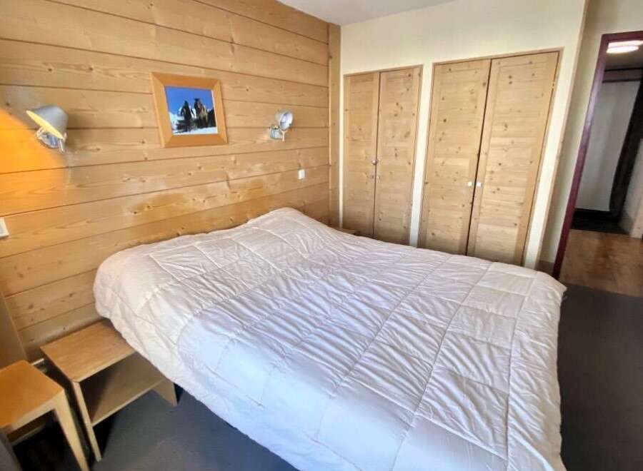 Cozy bedroom with wooden paneling and a comfortable bed.
