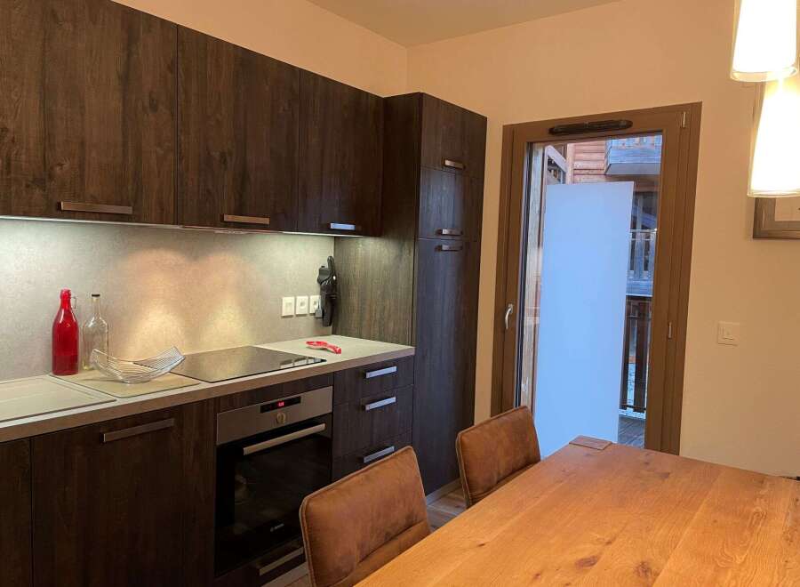 Discover a modern kitchen with sleek dark wood cabinetry and a stainless steel backsplash.