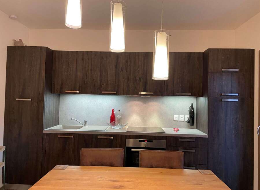 Modern kitchen with sleek dark wood cabinetry and stainless steel appliances.