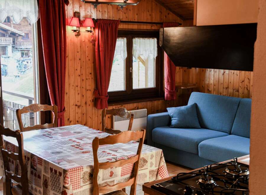 Cozy cabin living at its finest! This charming space features a dining area with a unique tablecloth and wooden chairs.