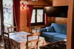 Cozy cabin living at its finest! This charming space features a dining area with a unique tablecloth and wooden chairs.