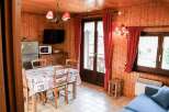 Cozy cabin interior featuring warm wood paneling and a charming dining area.