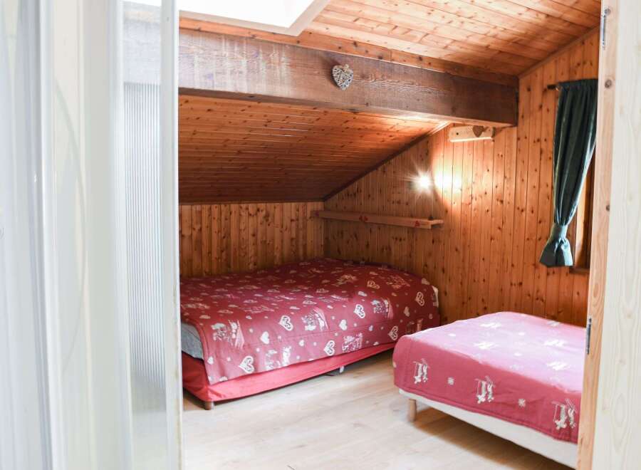 Cozy bedroom with wooden walls and ceiling, creating a warm and inviting atmosphere.