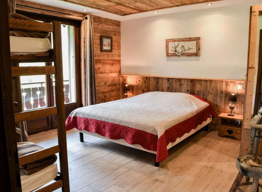 Cozy bedroom with wooden walls and ceiling, creating a warm and inviting atmosphere.