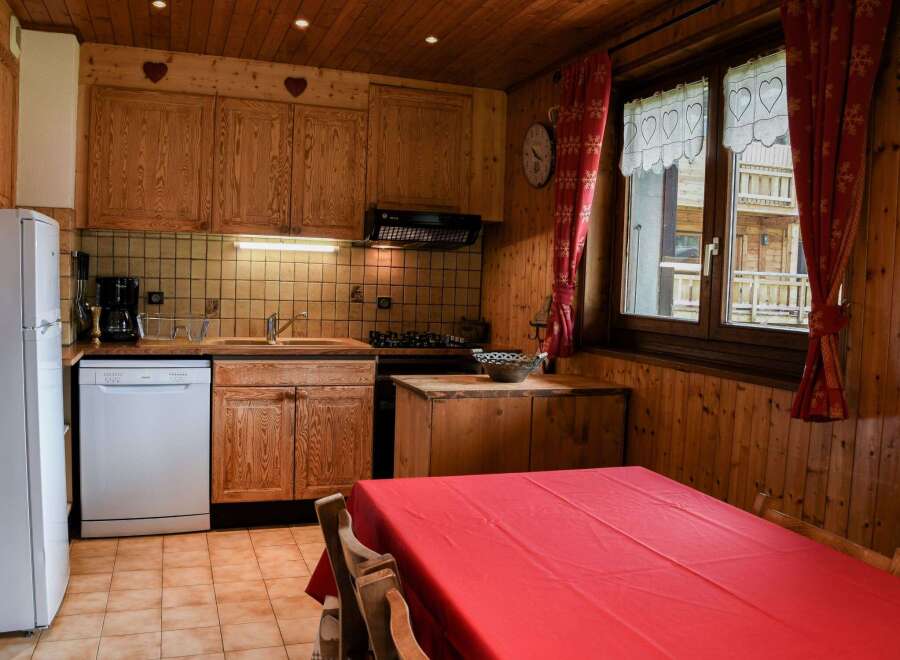 Cozy kitchen with wooden cabinets and a charming red tablecloth.