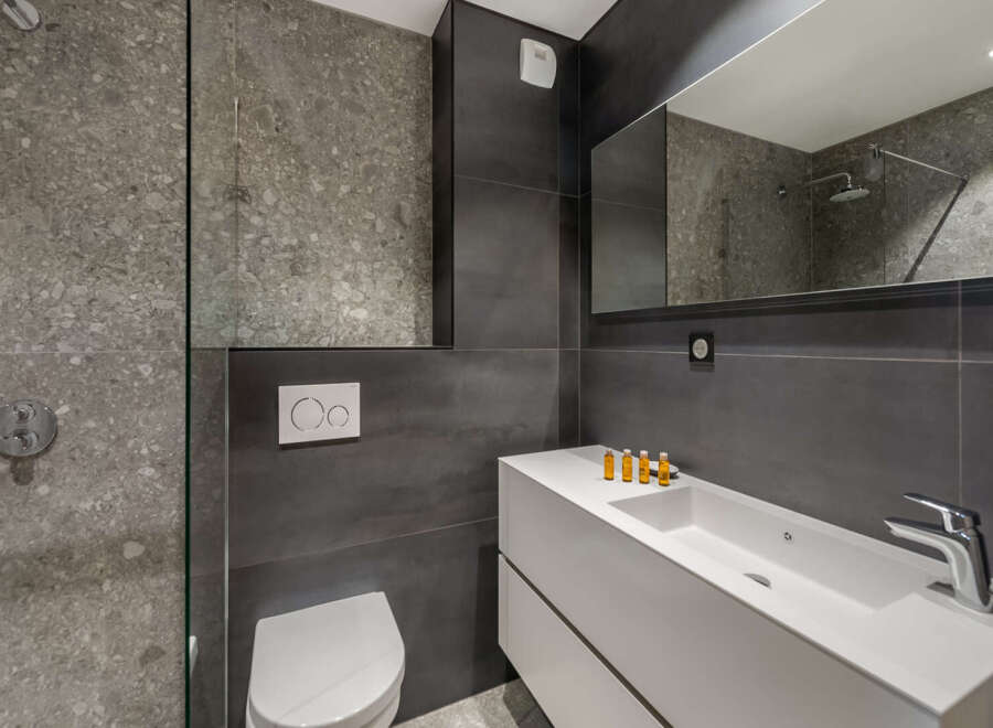 Modern bathroom design featuring sleek gray tiles and a minimalist white vanity.