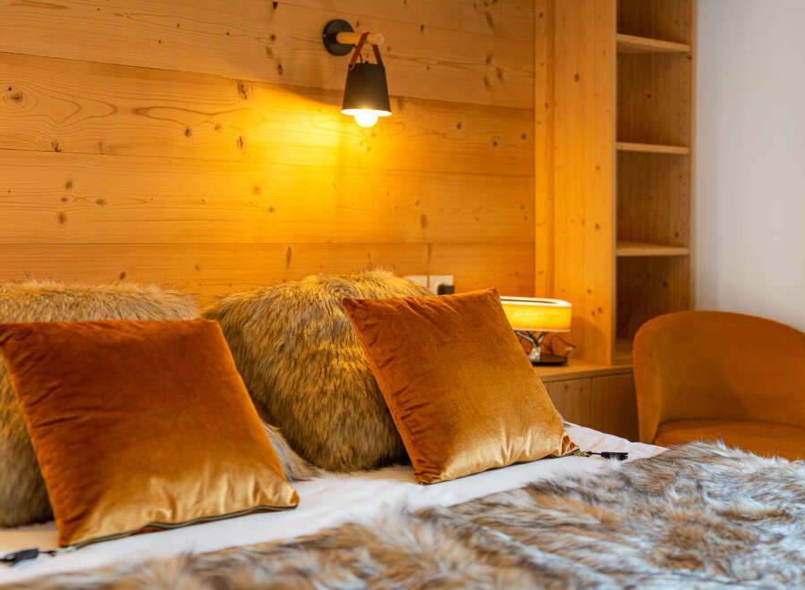 Cozy up in this inviting bedroom, featuring a plush bed adorned with luxurious pillows and a faux fur throw.