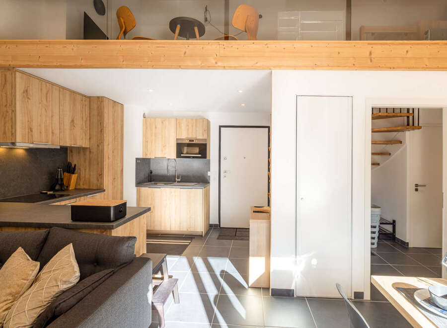 Discover a stylish and modern apartment with a well-equipped kitchen featuring sleek countertops and wooden cabinetry.