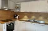 Modern kitchen with sleek white cabinets and a stylish wooden backsplash.