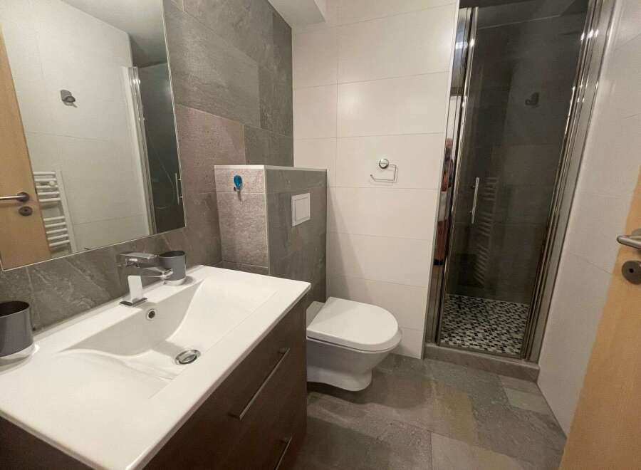 This modern bathroom features a sleek design with a spacious shower and a stylish vanity.