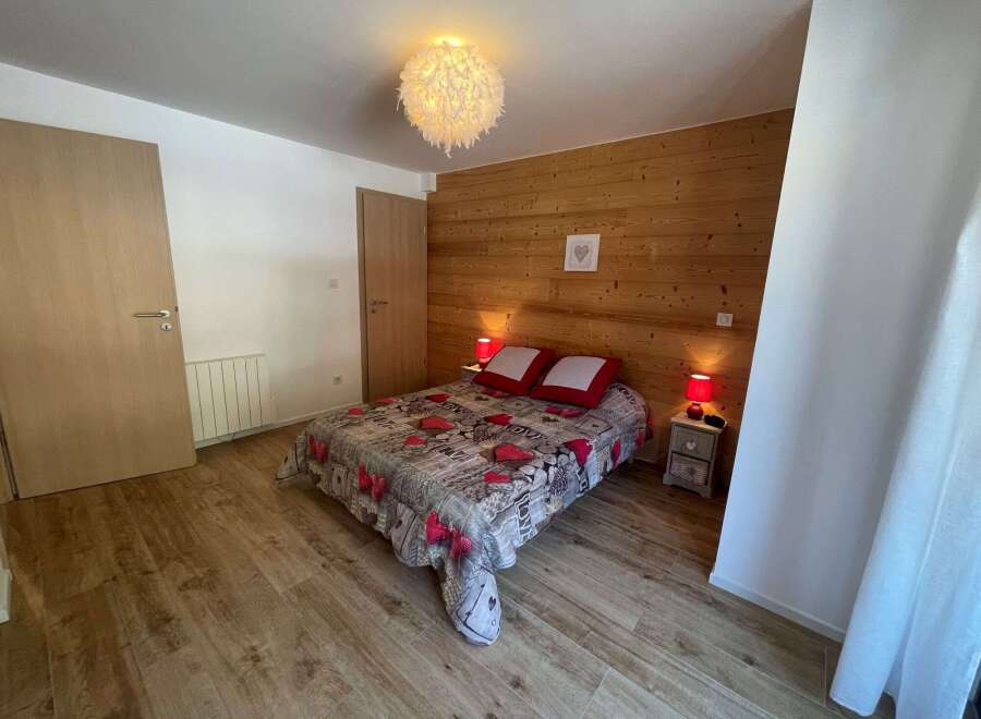 Cozy bedroom with a warm wooden accent wall and a comfortable bed.