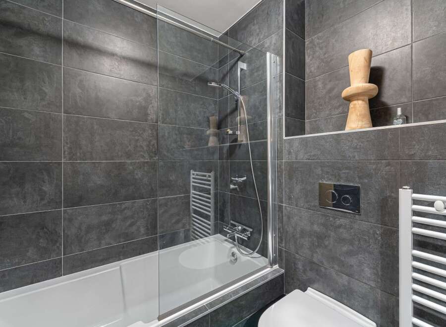 Modern bathroom design featuring sleek gray tiles and a glass shower enclosure.