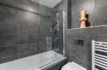 Modern bathroom design featuring sleek gray tiles and a glass shower enclosure.