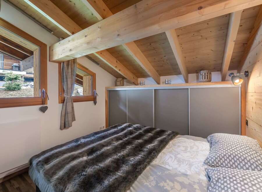 Cozy bedroom with wooden beams and a plush faux fur blanket.