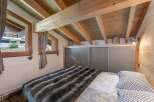 Cozy bedroom with wooden beams and a plush faux fur blanket.