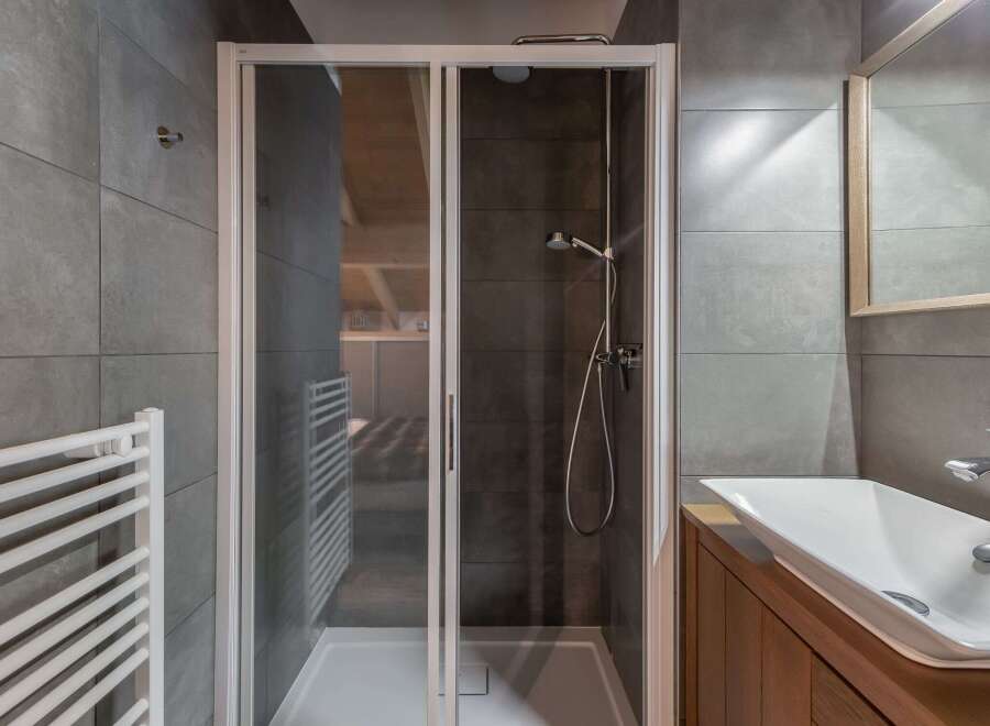 This modern bathroom features a sleek glass shower enclosure, perfect for a refreshing start to your day.