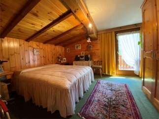 Cozy bedroom with wooden walls and ceiling, creating a warm and inviting atmosphere.