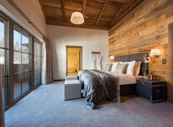 Experience luxury in this stunning bedroom featuring a cozy wooden ceiling and walls.