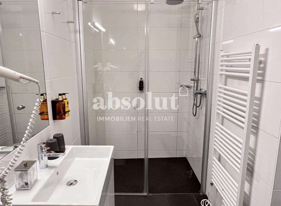 Discover a modern bathroom with a sleek glass shower and a convenient towel warmer.