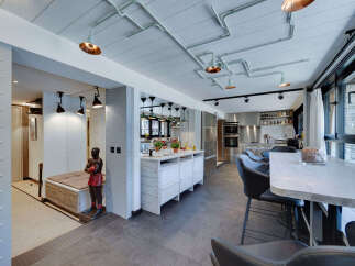 This modern kitchen boasts a unique industrial design with exposed pipes and stylish lighting fixtures.
