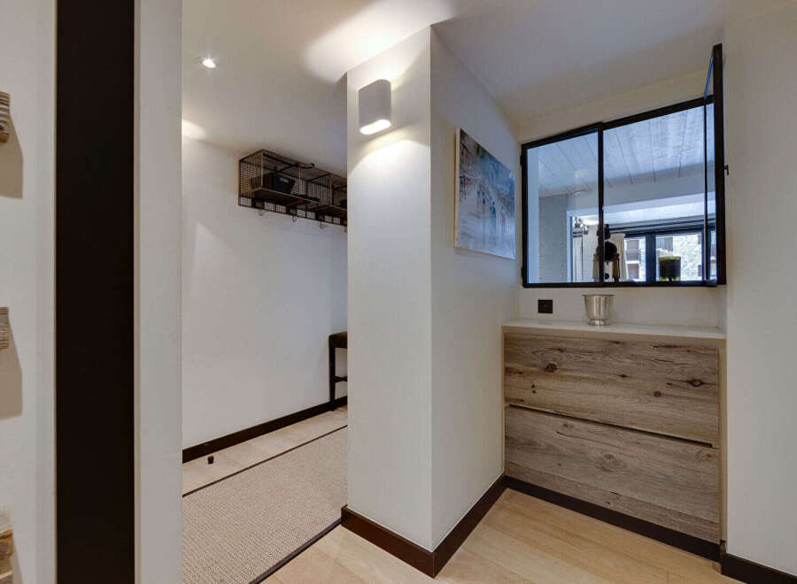 This hallway features a rustic wooden dresser with two drawers, topped with a light-colored counter and a silver bucket.