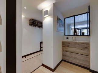 This hallway features a rustic wooden dresser with two drawers, topped with a light-colored counter and a silver bucket.