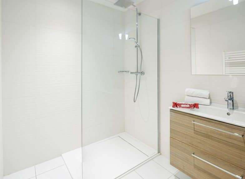 This modern bathroom features a sleek glass shower enclosure and a stylish vanity with ample storage.