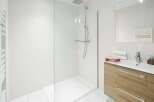 This modern bathroom features a sleek glass shower enclosure and a stylish vanity with ample storage.