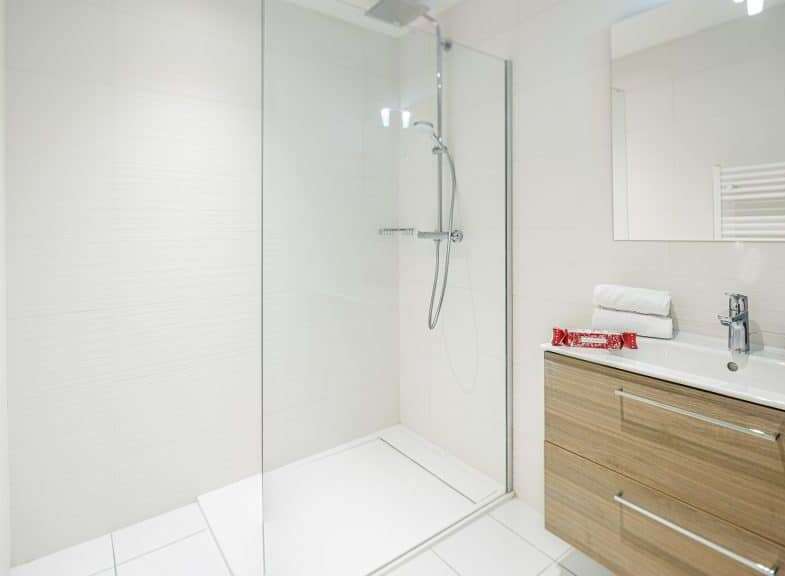 This modern bathroom features a sleek glass shower enclosure and a stylish vanity with ample storage.