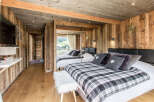 Experience rustic charm in this cozy bedroom, featuring warm wooden walls and a stylish plaid blanket.