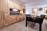 This stunning apartment boasts a modern kitchen with sleek wooden cabinetry and a spacious dining area, perfect for entertaining guests.