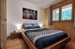 Cozy bedroom with a rustic wooden bed and a large window overlooking a forest.
