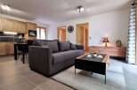 This stunning apartment boasts an open-plan living area with a comfortable grey sofa, a stylish coffee table, and a modern kitchen with wooden cabinets.