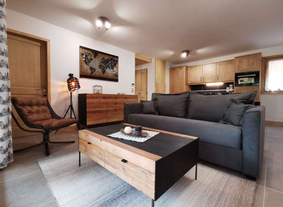 This stunning apartment boasts a spacious living area with a comfortable grey sofa, a stylish wooden coffee table, and a cozy armchair.