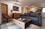This stunning apartment boasts a spacious living area with a comfortable grey sofa, a stylish wooden coffee table, and a cozy armchair.