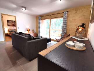 This stunning apartment boasts a spacious living area with floor-to-ceiling windows offering breathtaking views of the surrounding forest.