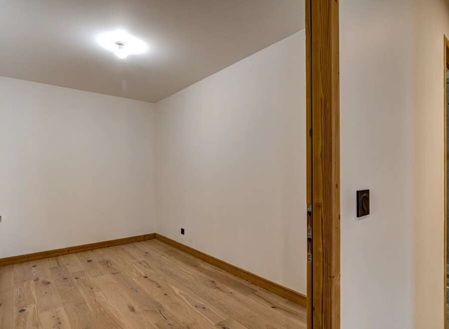 Step into this inviting space, featuring a warm wooden floor and pristine white walls.
