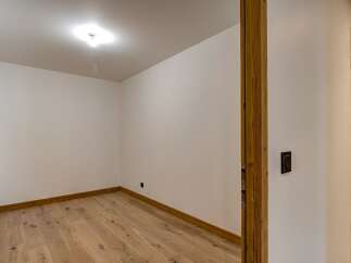 Step into this inviting space, featuring a warm wooden floor and pristine white walls.
