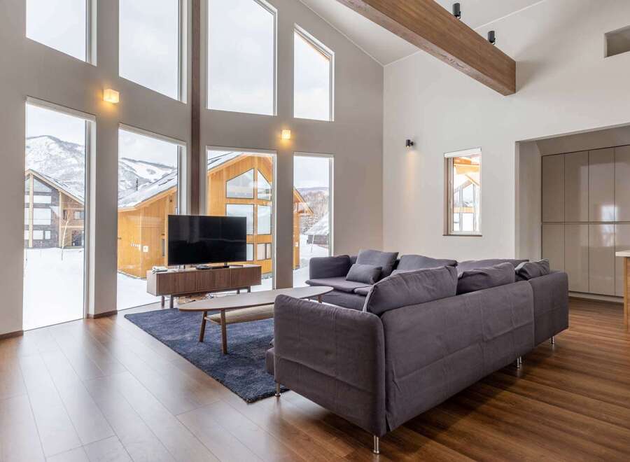 This stunning vacation home boasts floor-to-ceiling windows offering breathtaking views of the snowy mountain landscape.