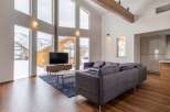 This stunning vacation home boasts floor-to-ceiling windows offering breathtaking views of the snowy mountain landscape.