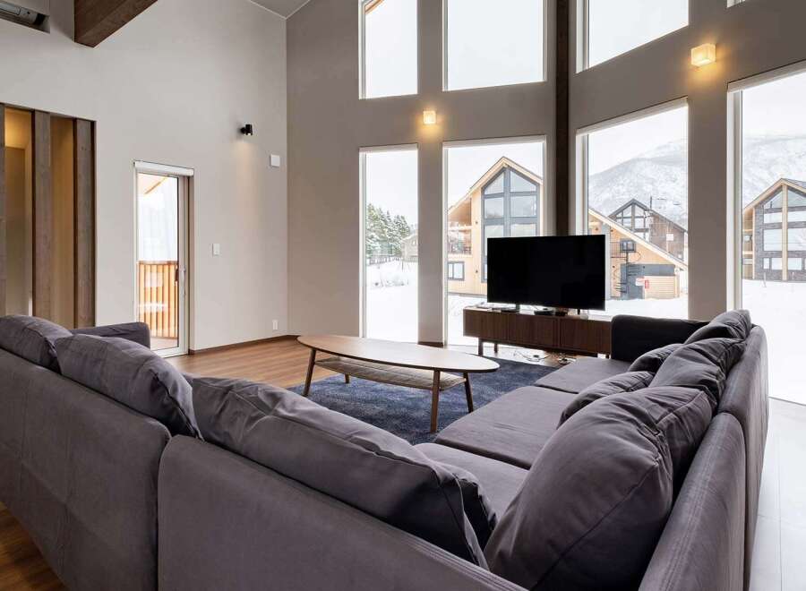 This stunning living room boasts floor-to-ceiling windows offering breathtaking views of a snow-covered landscape.