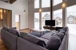 This stunning living room boasts floor-to-ceiling windows offering breathtaking views of a snow-covered landscape.