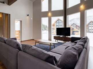 This stunning living room boasts floor-to-ceiling windows offering breathtaking views of a snow-covered landscape.