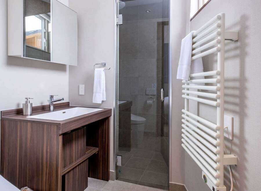 This modern bathroom boasts a sleek, dark wood vanity with a built-in sink and ample storage.