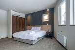 This modern bedroom boasts a comfortable king-size bed with plush bedding, a spacious closet, and large windows offering ample natural light.