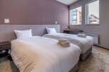 This cozy bedroom features two twin beds with plush white bedding, perfect for a relaxing stay.